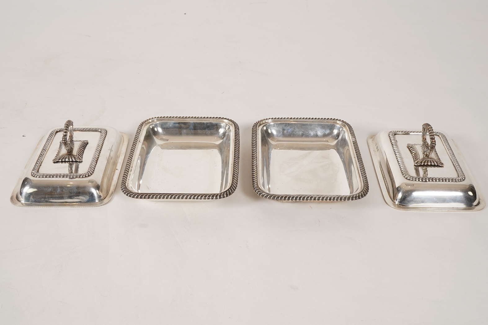 A matched pair of George V silver rectangular entrée dishes and covers, both with gadrooned borders and similar unmarked handles, Ellis & Co, Birmingham, 1923 and Ellis & Co, Birmingham, 1932, base 27.8cm, 108.3oz, exclu